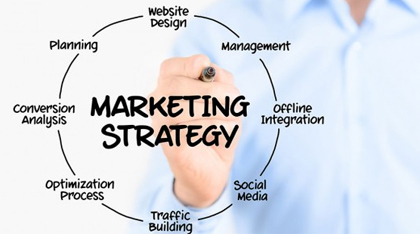 Man holding a pen with the words 'marketing strategy' inside a circle and related words around it.