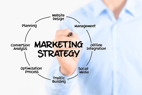 Man holding a pen with the words 'marketing strategy' inside a circle and related words around it.